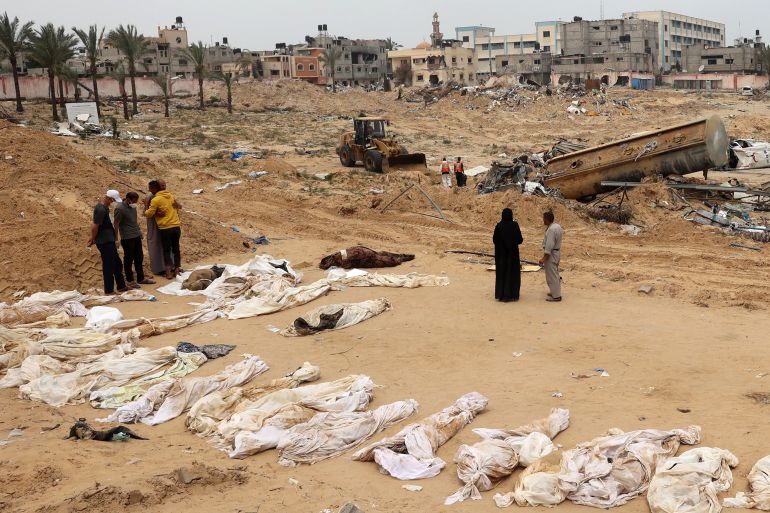 People gather near bodies lined up for identification after they were unearthed from a mass grave found in the Nasser Medical Complex in the southern Gaza Strip on April 25