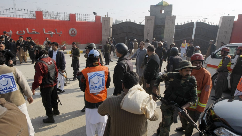 Pakistani troops and rescue workers gather at the main gate of Bacha Khan University in Charsadda town [AP]