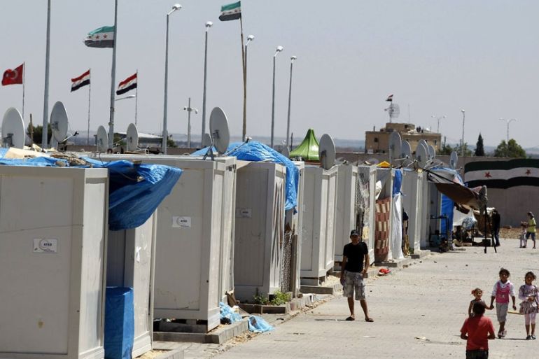 Syrian refugees stroll at a refugee camp named "Container City" on the Turkish-Syrian border