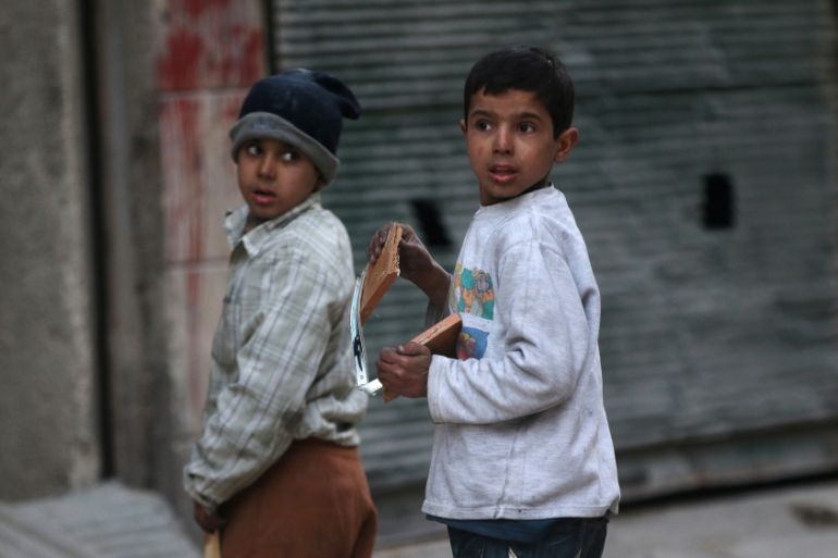 Boys collect firewood to be used for heating in a rebel-held besieged area of Aleppo