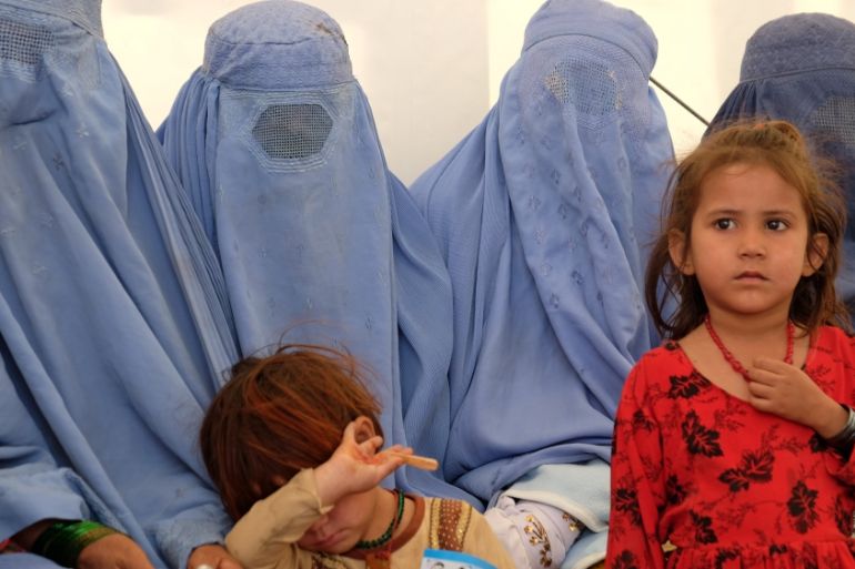 Afghan women, who were living as refugees in Pakistan, wait with their children at a humanitarian aid centre after their return, in Torkham, Afghanistan