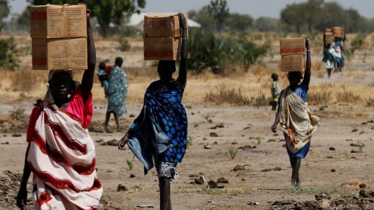 Women carry boxes of nutritional food delivered by the UN World Food Programme, in Rubkuai village, Unity State
