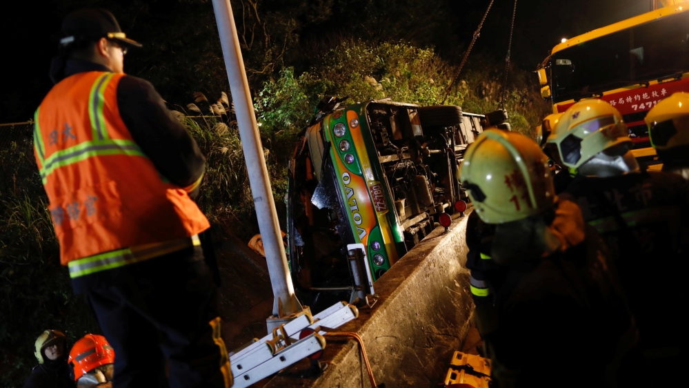 Rescuers gather around the crashed bus on an expressway in Taipei [Tyrone Siu/Reuters]