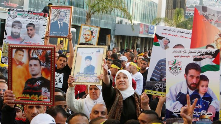 Palestinians hold pictures of relatives held in Israeli jails during a rally marking Palestinian Prisoner Day in the West Bank city of Nablus