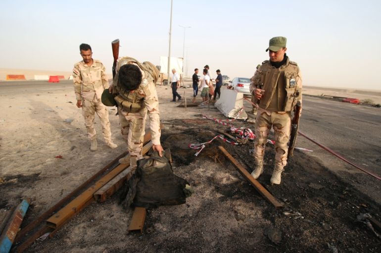 Iraqi soldiers inspect the site of a suicide car bombing on a highway near oilfields in southern Basra