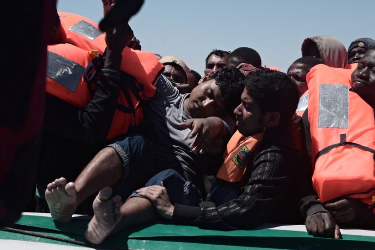 Migrants in an overcrowded plastic raft reach out for life jackets during a search and rescue operation by rescue ship Aquarius, operated by SOS Mediterranean and Doctors without Borders