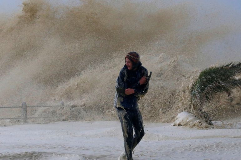 A man runs from sea spray as storms hit Cape Town