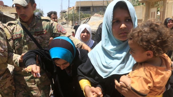 Iraqi rapid response forces help displaced Iraqi women who fled homes during a fight between Iraqi forces and Islamic State militants in al-Zanjili neighbourhood