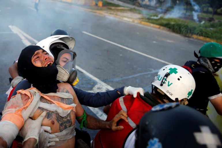 An injured opposition supporter is helped by volunteer members of a primary care response team during clashes with riot security forces at a rally against Venezuelan President Maduro