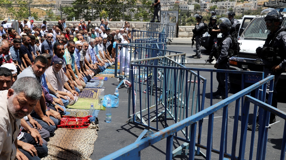 Israeli policemen stood guard as Palestinian men took part in Friday prayers outside Jerusalem's Old City [Ammar Awad/Reuters]