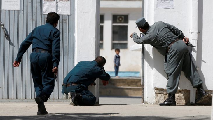 Afghan policemen try to rescue a child at the site of a suicide attack followed by a clash between Afghan forces and insurgents after an attack on a Shi''ite Muslim mosque in Kabul