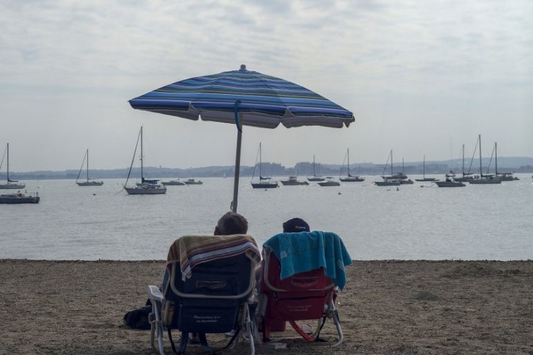 A couple sits under an umbrella on M Street Beach in South Boston, Massachusetts, US