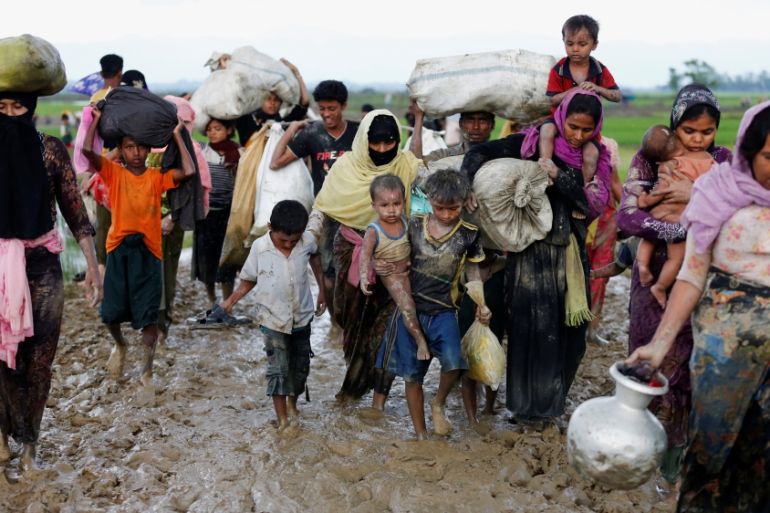 A group of Rohingya refugees walk on the muddy road after travelling over the Bangladesh-Myanmar border in Teknaf