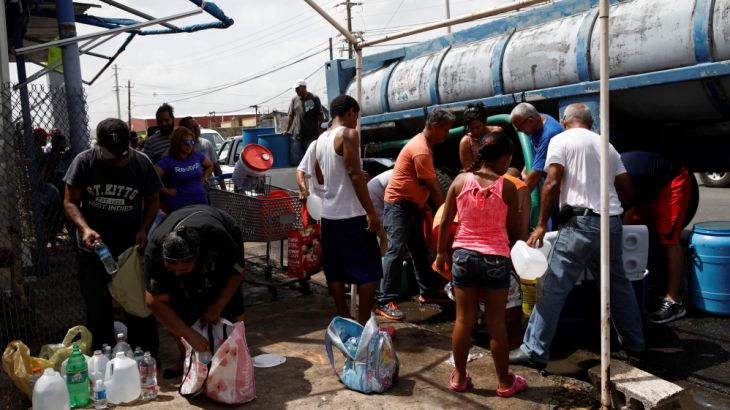 People queue to fill containers with water from a tank truck after the area was hit by Hurricane Maria in Canovanas