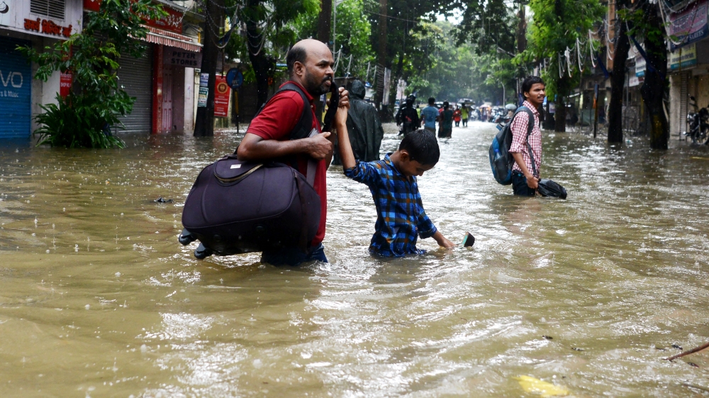 Indians wade through a flooded street during heavy rain showers in Mumbai [Punit Paranjpe/AFP]