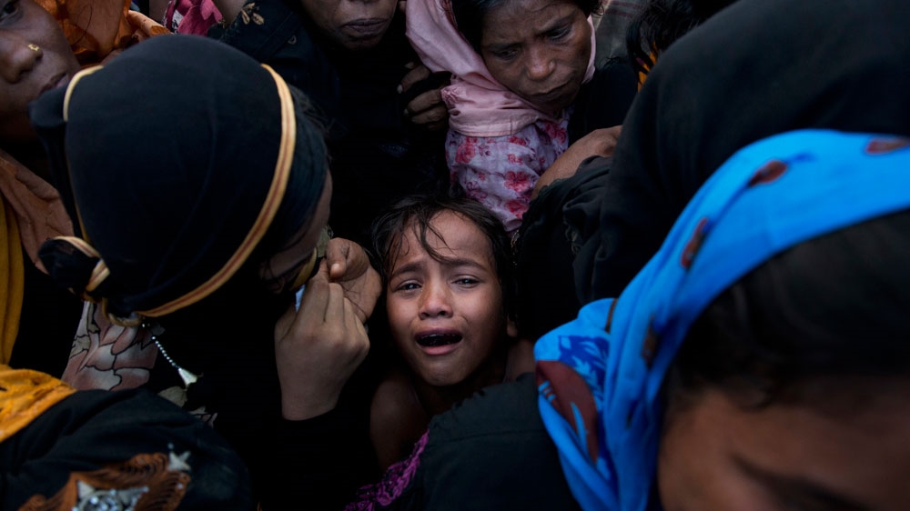 A Rohingya child cries amid a crowd of elders to receive food being distributed [AP]