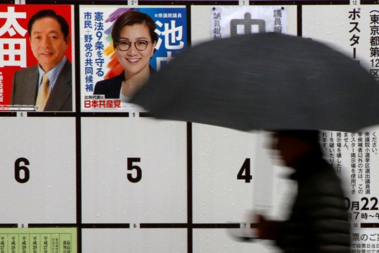 A man walks in the rain past election posters near a polling station as Typhoon Lan approaches Japan''s mainland, in Tokyo