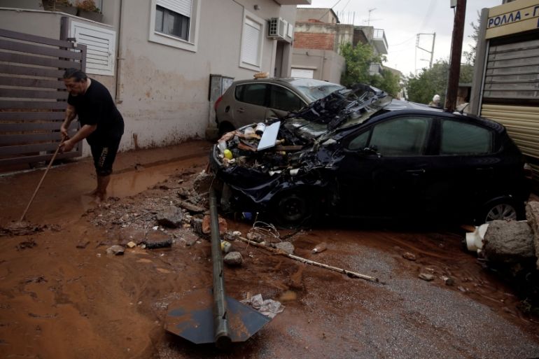 A local cleans the mud from the street following heavy rainfall in the town of Mandra
