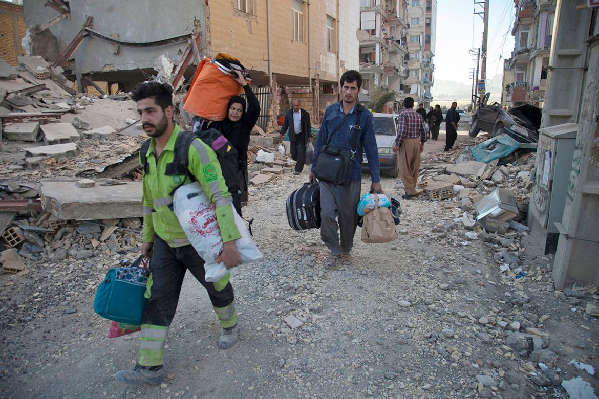 In this photo provided by Tasnim News Agency, people carry their belongings in Sarpol-e-Zahab, western Iran, Monday, Nov. 13, 2017. Authorities reported that a powerful 7.3 magnitude earthquake struck