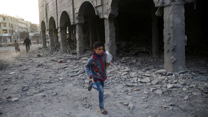 A Syrian boy runs past a damaged building in Douma, in the eastern Damascus suburb of Ghouta