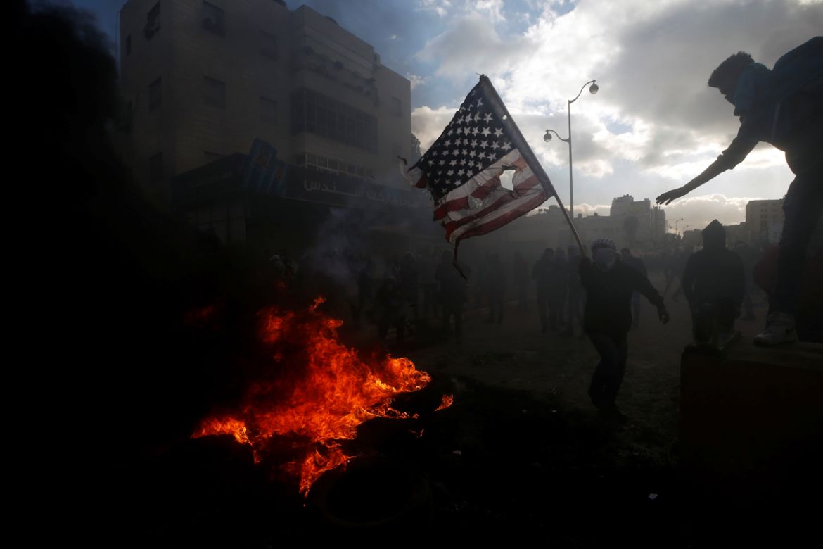 A Palestinian protester prepares to burn a U.S. flag during clashes with Israeli troops at a protest against U.S. President Donald Trump''s decision to recognise Jerusalem as the capital of Israel, nea
