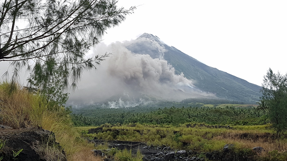 Smoke plumes rise off of Mt Mayon as the volcano spews out lava that smoulders in the rain [JC Gotinga/Al Jazeera]