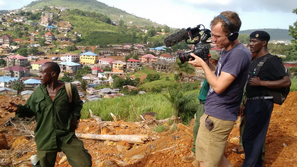 Paul Glynn (on camera) filming at Sugarloaf Mountain in Regent, Sierra Leone, the site of the landslide. [Al Jazeera]