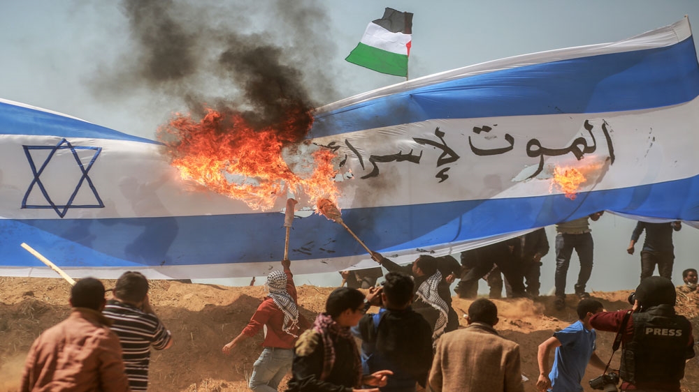 Palestinians in Gaza burn the Israeli flag as part of the protest's theme on the third consecutive Friday [Hosam Salem/Al Jazeera] 