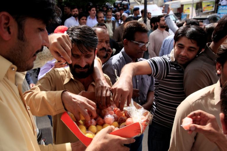 Supporters of the opposition Tehreek-e-Insaf (PTI) party distribute sweets to celebrate disqualification of Foreign Minister Khawaja Asif from parliament, in Islamabad