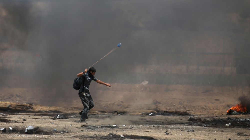 A Palestinian demonstrator uses a sling to hurl stones at Israeli troops at the Israel-Gaza border [Ibraheem Abu Mustafa/Reuters]