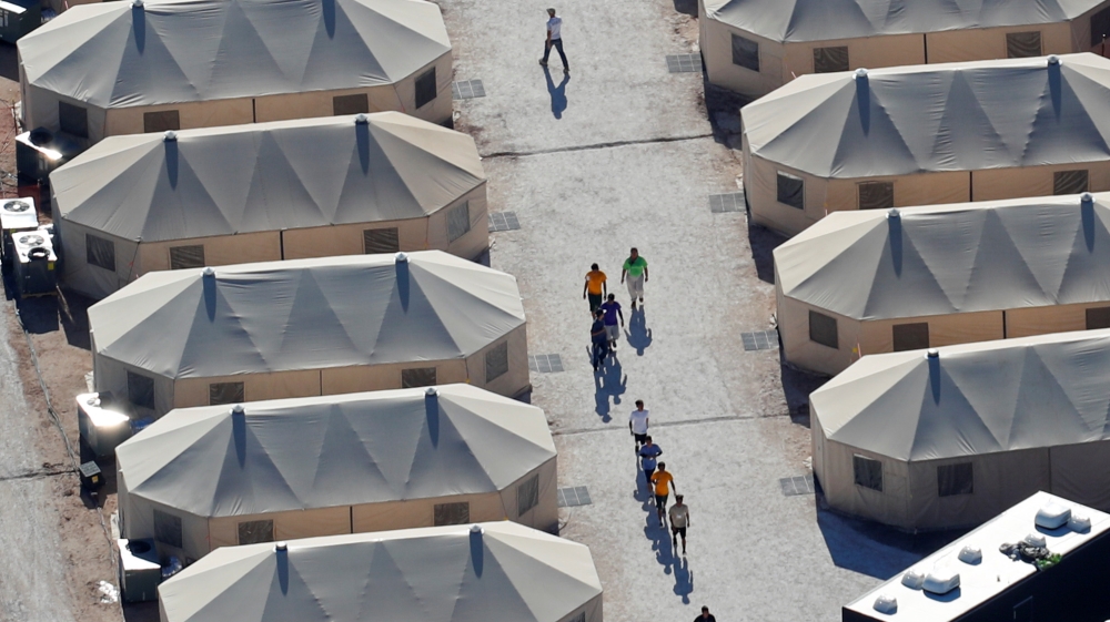 Immigrant children, many of whom have been separated from their parents are shown walking in single file between tents in their compound next to the Mexican border in Tornillo, Texas [Mike Blake/Reuters]