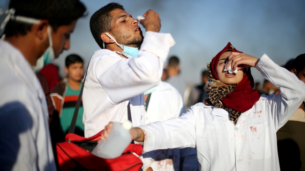 Razan al-Najjar (R) reacting to tear gas during an April 1 rally in the southern Gaza Strip [File: Ibraheem Abu Mustafa/Reuters]