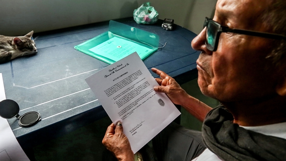 Prada, one of the FARC's founding fathers, receives his official accreditiation[Lukas Rapp/Al Jazeera]