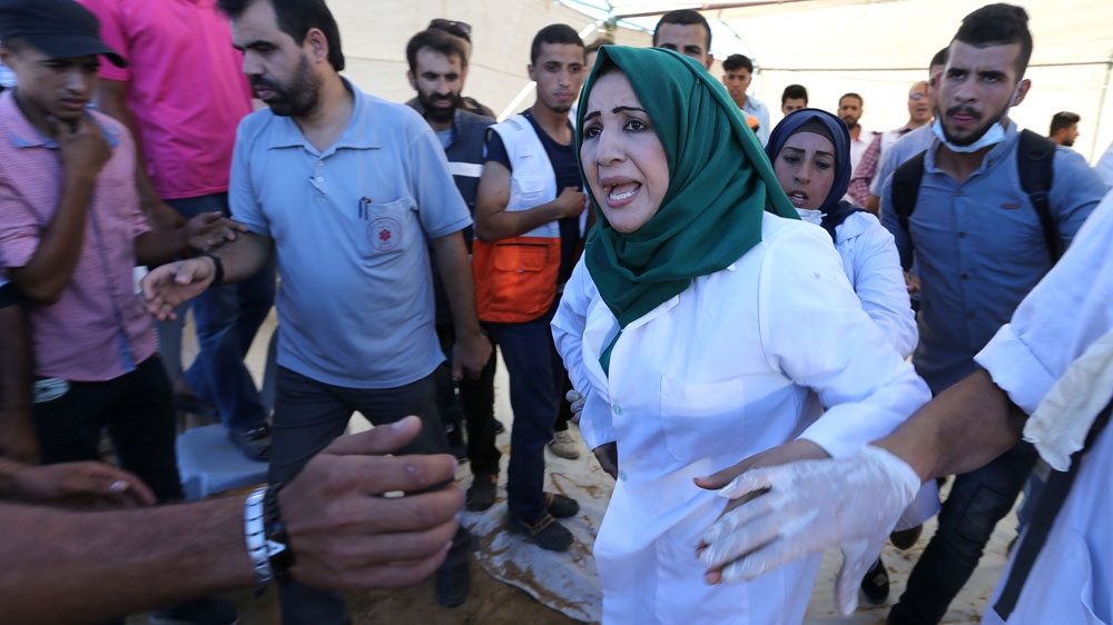 A Palestinian nurse reacts upon seeing the body of her husband who was killed by Israeli troops during Friday's protest. [Ibraheem Abu Mustafa/Reuters]