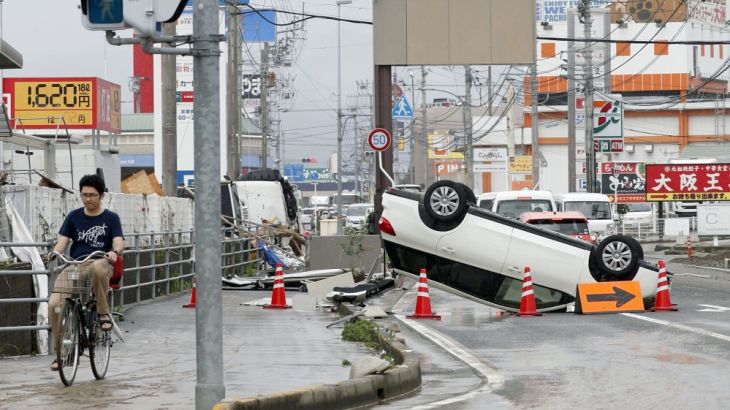 An overturned car remains on a street after heavy rain in Ozu, Ehime Prefecture, Japan