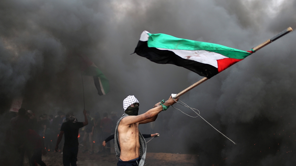 A demonstrator waves a Palestinian flag during a protest calling for lifting the blockade on Gaza [Mohammed Salem/Reuters]