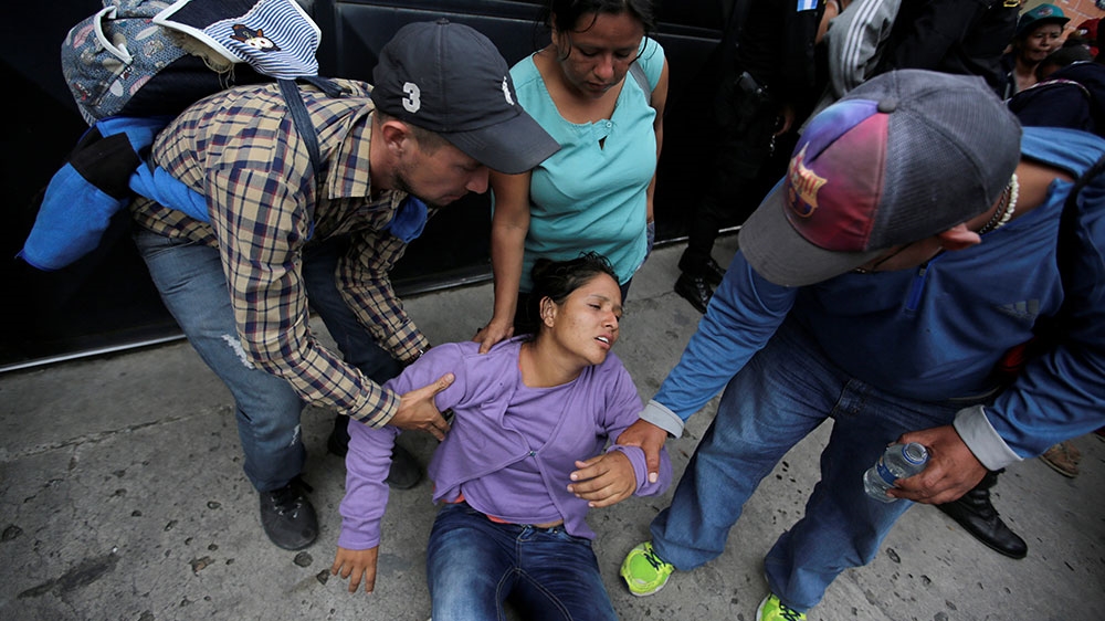 A Honduran migrant, part of a caravan trying to reach the US, is helped by others after arriving in Esquipulas city in Guatemala [Jorge Cabrera/Reuters]