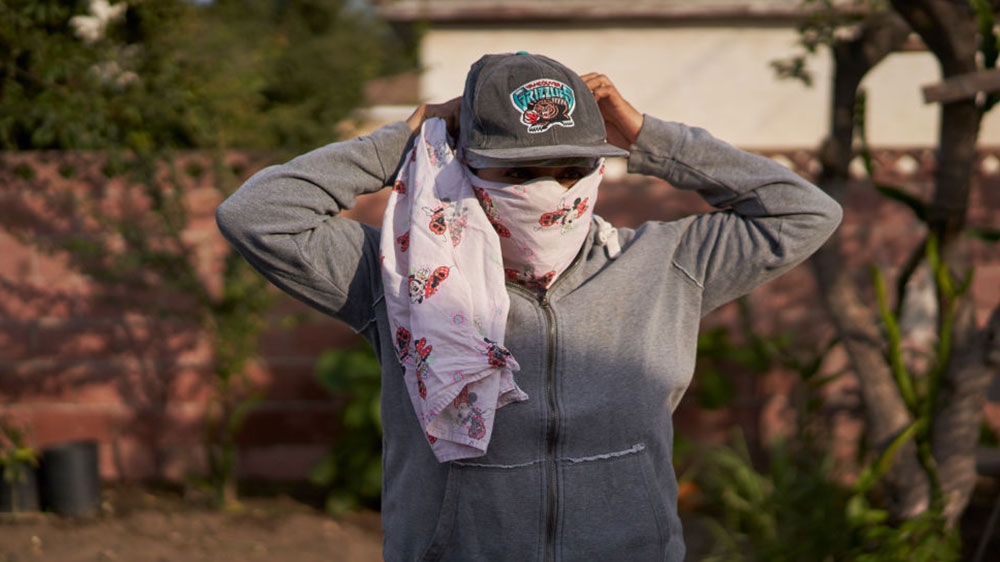 An undocumented woman wears a bandana she used to cover her nose and mouth to avoid inhaling smoke while working in the fields during the Hill Fire [Philip Cheung for The Washington Post/Getty Images] 