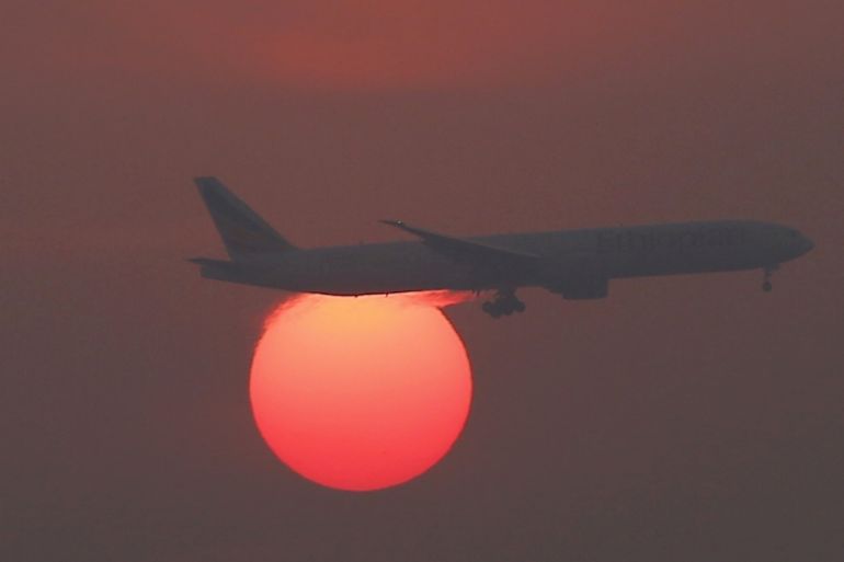A plane flies over the setting sun in the sky at Beijing International Airport