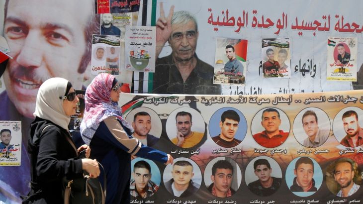 Women walk past pictures of Palestinian prisoners
