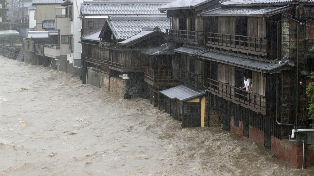 Men watch the swollen Isuzu River due to heavy rain caused by Typhoon Hagibis in Ise