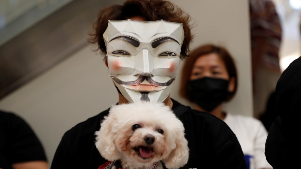 An anti-government protester holding a dog wears a mask during a demonstration at New Town Plaza shopping mall in Hong Kong