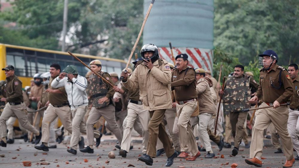Police chasing protesters outside the Jamia Millia Islamia university in New Delhi