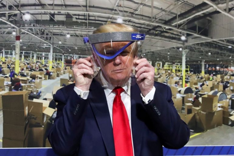 U.S. President Donald Trump holds up a protective face shield during a tour of the Ford Rawsonville Components Plant that is manufacturing ventilators, masks and other medical supplies during the coro