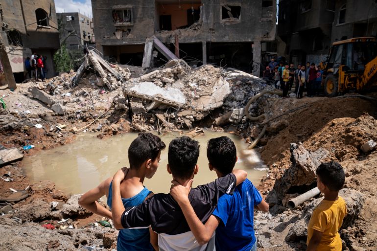 Children gather beside the crater where homes were destroyed by an air attack on Gaza