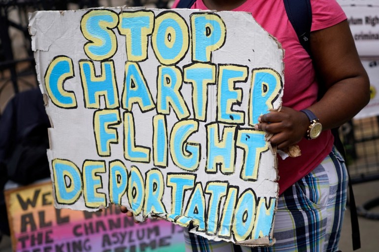 A protester holds a placard that reads 'Stop charter flight deportation' during a demonstration outside the Home Office in London, UK.