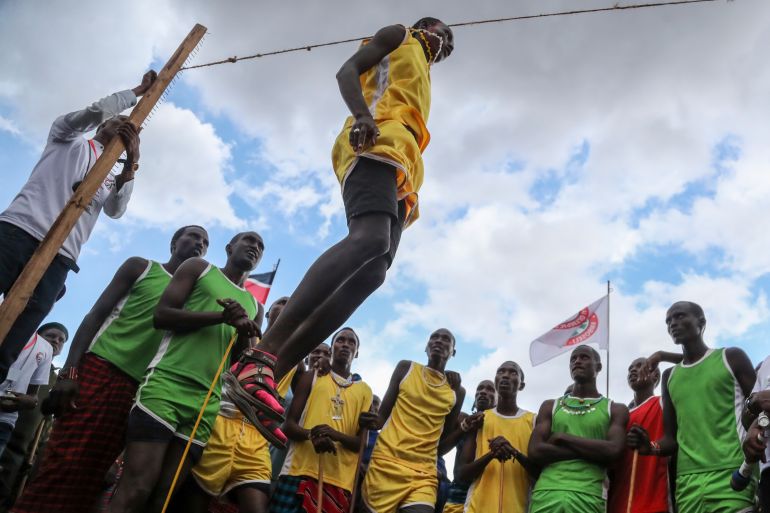 A Maasai man competes in the high-jump competition at the Maasai Olympics, surrounded by onlookers, in Kimana Sanctuary, Kenya.