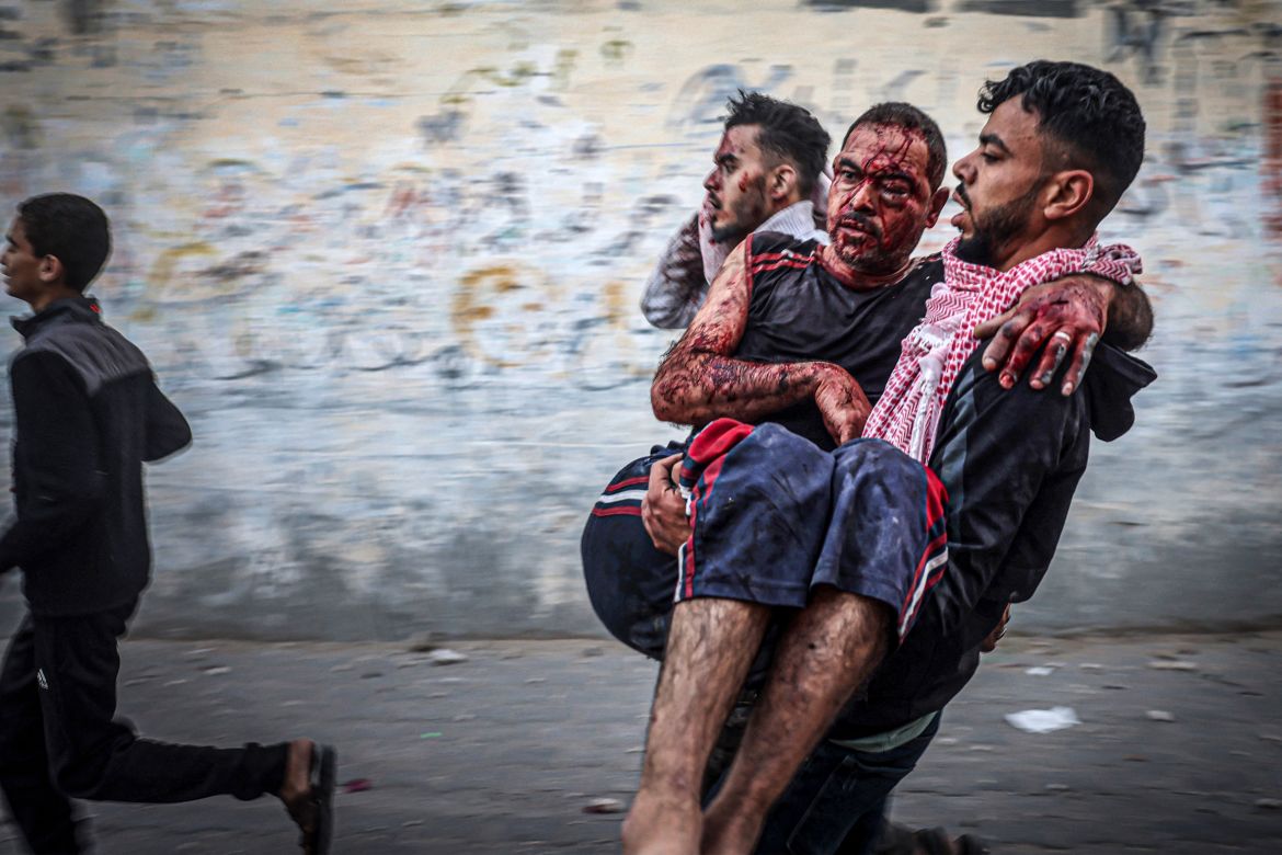 A Palestinian man carries an injured man as people flee following an Israeli strike in Rafah in the southern Gaza Strip.