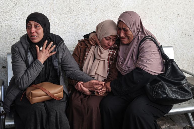 Palestinians mourn over the covered bodies of relatives, killed in overnight Israeli bombardment