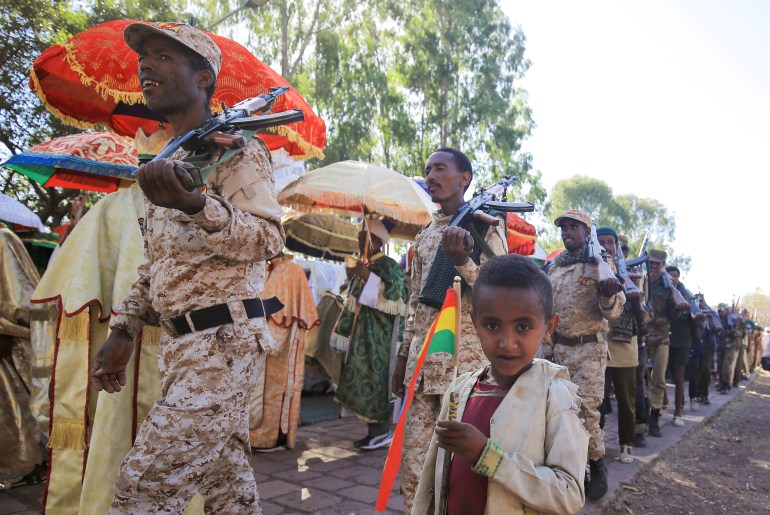 A boy holds the Ethiopia's national flag as the Amhara Special Forces' members march during the annual St. George's Day celebrations at the Saint George rock-hewn church in the Lalibela town of the Amhara Region, Ethiopia, January 25, 2022. Picture taken January 25, 2022. REUTERS/Tiksa Negeri